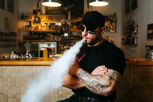 Buy Cannabis Products Online image of a bearded man vaping in a cannabis dispensary.