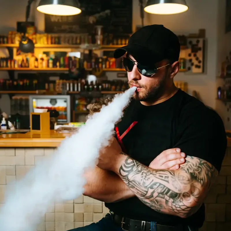 Buy Cannabis Products Online image of a bearded man vaping in a cannabis dispensary.